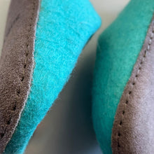 Close-up of aqua blue felted wool slippers showing suede sole stitching and wool texture.