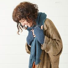 Woman wearing a soft blue banana yarn scarf and chunky knit wrist warmers styled with a relaxed neutral coat.