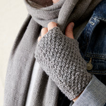 Detailed close-up of grey knitted fingerless gloves paired with a soft woven winter scarf.