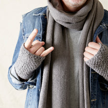 Close-up of a man wearing a grey knit scarf and matching fingerless gloves with a blue denim jacket for winter styling.