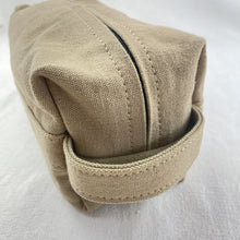 Close-up of beige handmade canvas zip pouch with durable zipper and side handle detail.