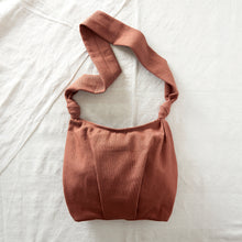 Terracotta brown handwoven cotton crossbody bag with roomy slouchy shape and long wide strap.