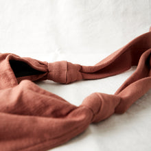 Close-up detail of terracotta brown cotton crossbody bag showing soft knotted strap and handwoven texture.