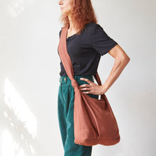 Terracotta brown cotton crossbody bag worn across the body with long comfortable strap.