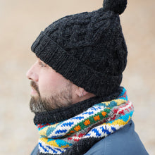 Man wearing dark grey cable knit wool bobble hat with pom pom, hand-knitted from 100% sheep wool by fair trade artisans in Nepal