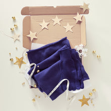 Pair of blue gloves and blue scarf gift boxed on a white surface with decorative stars and gold accents.