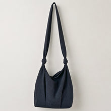 Handmade black cotton shoulder bag with adjustable knotted straps on white background