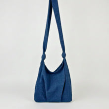 Woman wearing handmade blue cotton crossbody bag with knotted strap and relaxed minimalist silhouette