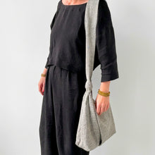 Woman wearing handmade grey cotton shoulder bag with knotted strap and relaxed artisan style
