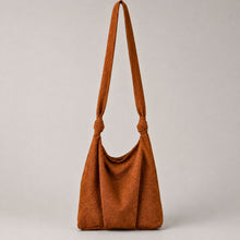 Woman wearing handmade rust cotton crossbody shoulder bag with adjustable knotted strap and minimalist design
