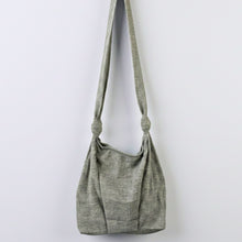 Handmade grey cotton shoulder bag with knotted straps displayed against neutral background