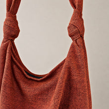 Close-up detail of handmade rust cotton hobo bag showing textured weave and knotted shoulder straps