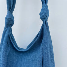 Close-up of handmade blue cotton hobo bag showing textured woven fabric and knotted strap detail