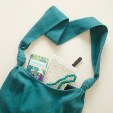 Teal green handwoven cotton crossbody bag showing roomy interior with everyday essentials inside.