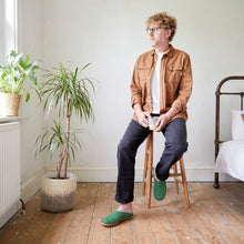 Man wearing green handmade wool slippers with suede soles while sitting at home.