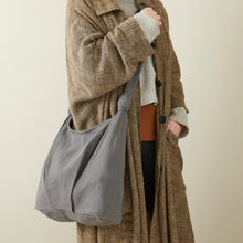 Grey handwoven cotton crossbody bag worn across the body with soft slouchy shape and long comfortable strap.