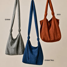 Three handmade cotton shoulder bags by AURA QUE including the grey GYANI crossbody bag, blue GYANI Tall shoulder bag and orange JOGI tote bag with knotted straps.