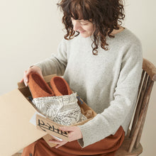 AURA QUE handmade wool slippers packed in a gift box with a cotton bag and care card.