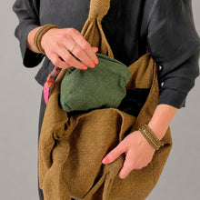 Handmade green cotton cosmetic pouch with colourful artisan zip pull placed inside textured artisan tote bag