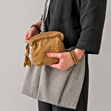 Woman holding handmade mustard cotton cosmetic pouch with artisan fabric zip pull and grey shoulder bag