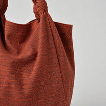 Close-up of a handmade amber orange cotton shoulder tote bag showing textured woven fabric and knotted strap detail