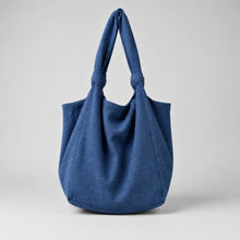 Handmade blue cotton tote bag with soft slouchy design and knotted shoulder straps on a neutral background