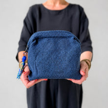 Woman holding handmade blue cotton makeup pouch with zip closure and artisan fabric pull detail