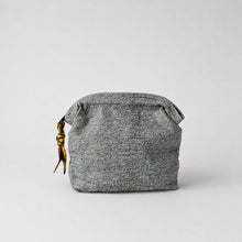 Handmade grey cotton cosmetic pouch with zip closure and artisan fabric zip pull on soft grey background