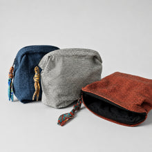 Three artisan handwoven cotton zip pouches in rust red, grey and navy blue displayed together on a neutral background.