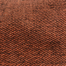 Close-up detail of rust red handwoven cotton fabric showing textured artisan weave pattern.