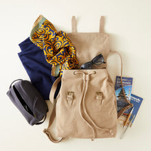 Beige handmade canvas backpack styled with scarf, sunglasses, travel guidebooks and navy organiser pouch.
