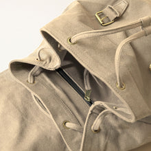 Close-up of beige cotton canvas backpack interior featuring drawstring closure and internal zip pocket.