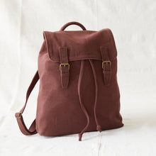 Brown cotton canvas backpack featuring flap closure, brass buckles and adjustable drawstring opening.