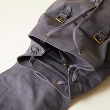 Close-up of grey cotton canvas backpack interior featuring drawstring closure and internal zip pocket.