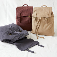 Brown and natural beige cotton canvas backpacks displayed with adjustable straps and brass buckle closures.