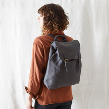 Woman wearing a grey cotton canvas backpack with minimalist everyday styling against a neutral backdrop.