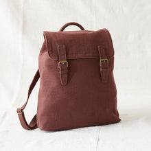 Front view of a brown cotton canvas backpack with brass buckle straps and minimalist design styling.