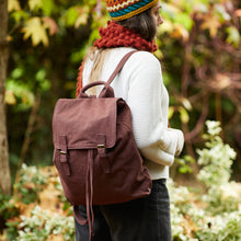 Woman wearing a brown cotton canvas backpack outdoors with knit winter accessories in an autumn setting.