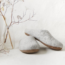 Light grey felted wool MITA mule slippers with stitched suede soles, styled with dried flowers.