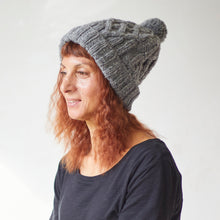 Woman wearing light grey cable knit wool bobble hat handmade from 100% sheep wool with soft pom pom detail