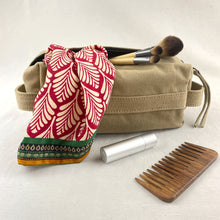 Beige canvas makeup pouch styled with scarf, makeup brushes, comb and sustainable beauty accessories.
