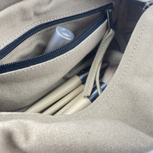 Interior detail of beige canvas organiser pouch showing zip pocket and storage compartments for accessories.