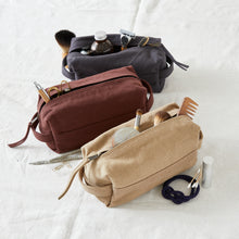 Canvas zip pouches in beige, rust and grey filled with makeup, grooming and stationery essentials.