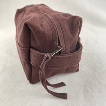 Side view detail of a handmade rust canvas zip pouch with sturdy handle and zipper closure.