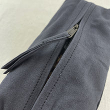 Detailed close-up of grey canvas zip pouch featuring durable zipper and handcrafted finish.