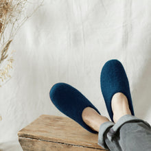 Person wearing navy wool MITA mule slippers at home with felted wool uppers and suede soles.