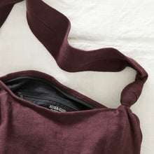 Plum purple cotton crossbody bag showing zip closure and black cotton lining detail.