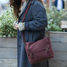 Woman wearing brown handmade canvas satchel crossbody bag with winter coat outdoors.