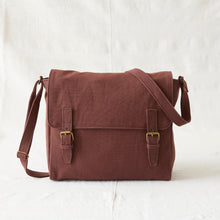Front view of brown handmade canvas messenger bag with brass buckles and adjustable shoulder strap.