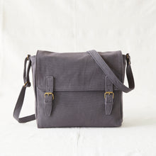 Front view of handmade grey canvas messenger bag with adjustable shoulder strap and brass buckle closures.